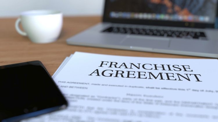 The words franchise agreement on a contract on a table.