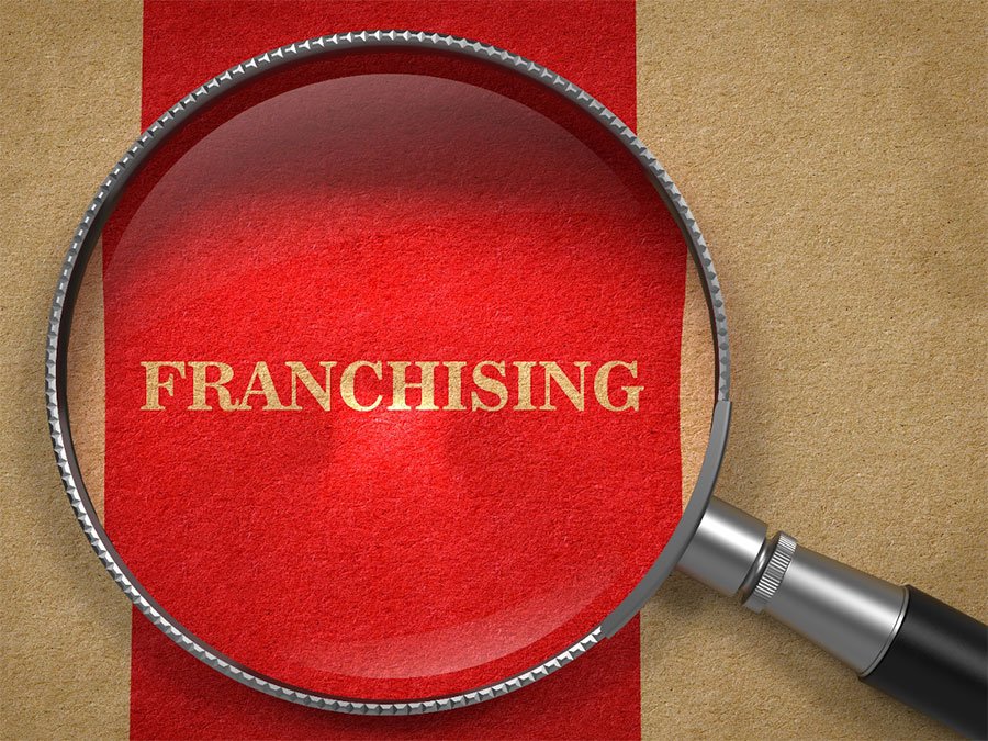 The word franchising in gold under a microscope.