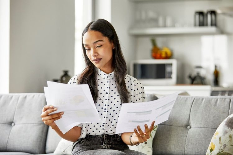 A woman looking at sheets of paper in both of her hands.