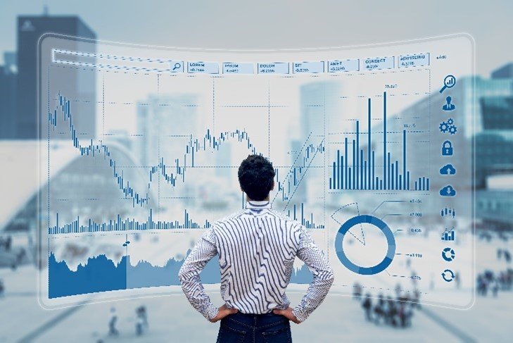 A man standing in front of a window screen with a lot of graphs.